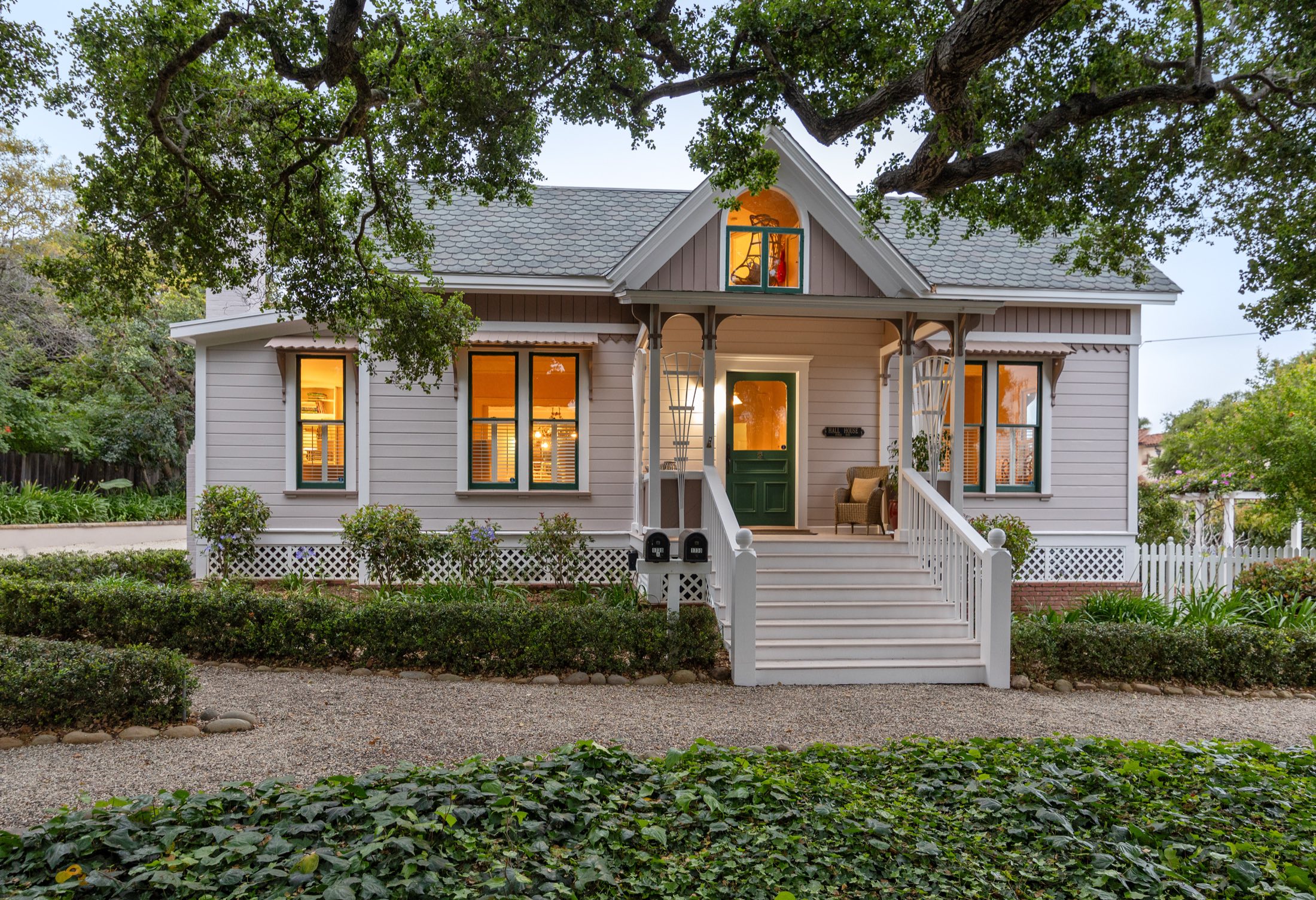 Anacapa at dusk — an 1888 Victorian with a wraparound porch, lit from within